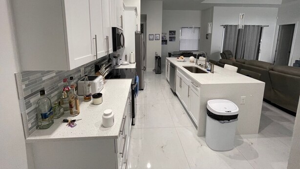 Una cocina moderna con armarios blancos, una isla central y un horno empotrado.