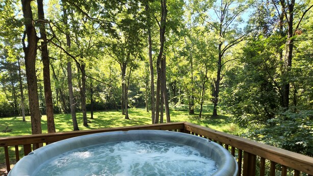 A hot tub on a wooden deck surrounded by a forest.