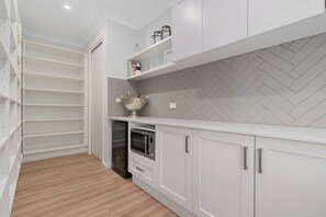 A modern kitchen with white cabinetry, a herringbone-patterned backsplash, and a built-in oven.