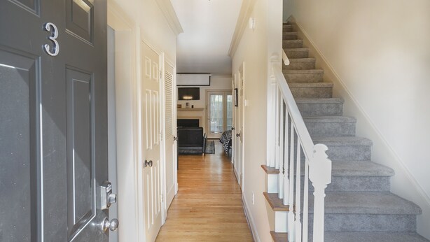 A hallway with a staircase, wooden flooring, and a door marked with the number 3. - Movie Nights Nash! 2bd Townhome off WEST END! 8 min-> DT! (Nashville)