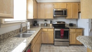 A kitchen with granite countertops, wooden cabinets, a stainless steel oven, a microwave, and a sink. - Movie Nights Nash! 2bd Townhome off WEST END! 8 min-> DT! (Nashville)