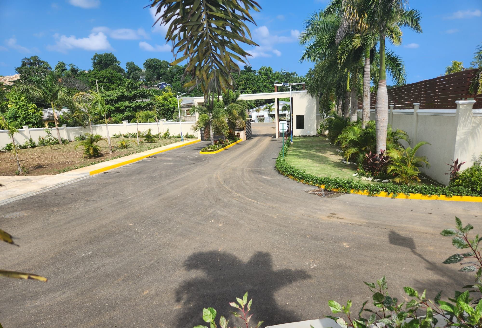 A road leading to a building with a white facade and a yellow curb.