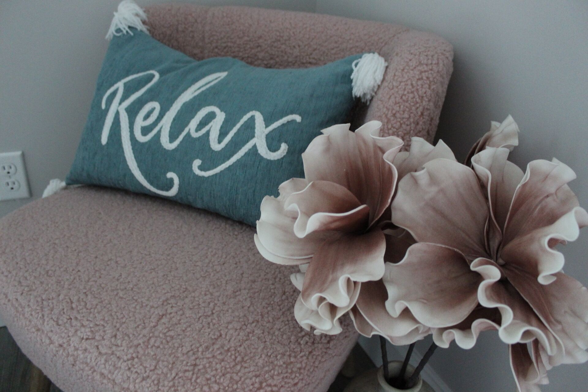 A chair with a 'Relax' pillow and a decorative flower arrangement.