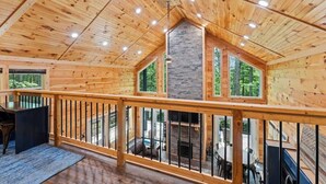 A spacious wooden cabin with a high ceiling, large windows, and a balcony with a railing. - 3BR 2BA w/ King Bed/Hot Tub in Heart of RRG (Campton)
