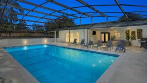 An indoor swimming pool with a glass ceiling, surrounded by lounge chairs and a patio area. - Luxury Ranch 2 Master Kg Bed w/ heated Salted Pool (Orlando)