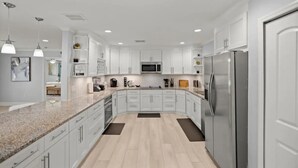 A modern kitchen with white cabinets, a stainless steel refrigerator, and granite countertops. - Luxury Ranch 2 Master Kg Bed w/ heated Salted Pool (Orlando)