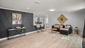 A modern living room with a dark accent wall, a dining area, and a decorative wall piece. - Luxury Ranch 2 Master Kg Bed w/ heated Salted Pool (Orlando)