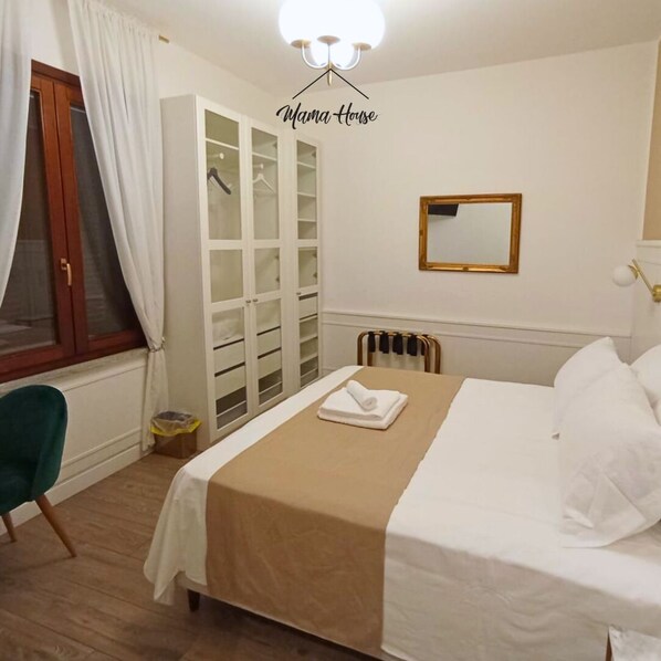 Habitación de hotel con cama, armario, espejo y radiador.