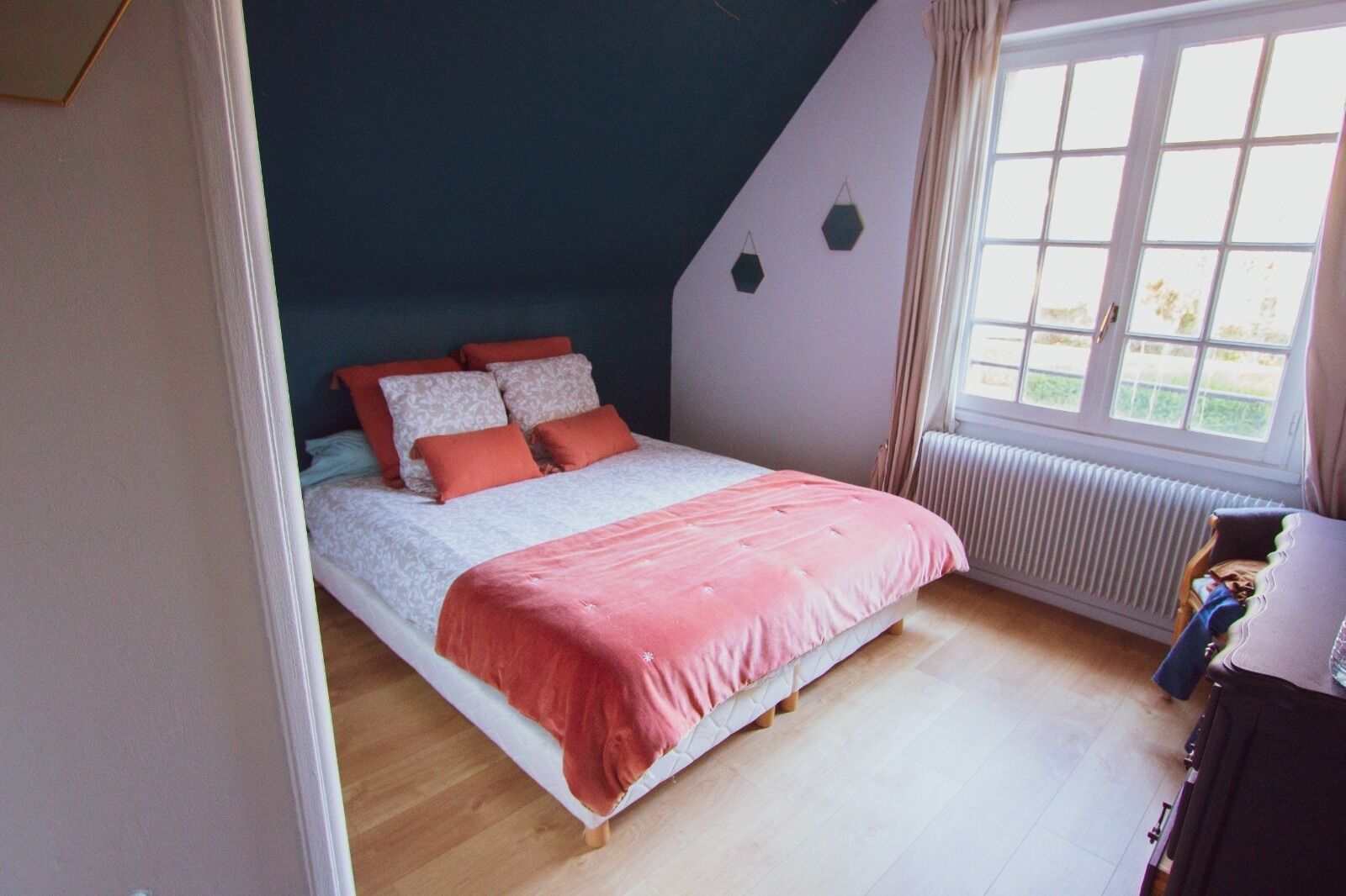 A bedroom with a bed, a radiator, and a window.