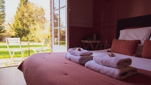 A bedroom with a large bed, a view of the outdoors, and a seating area with chairs. - les jardins de Beaumont (Hem)