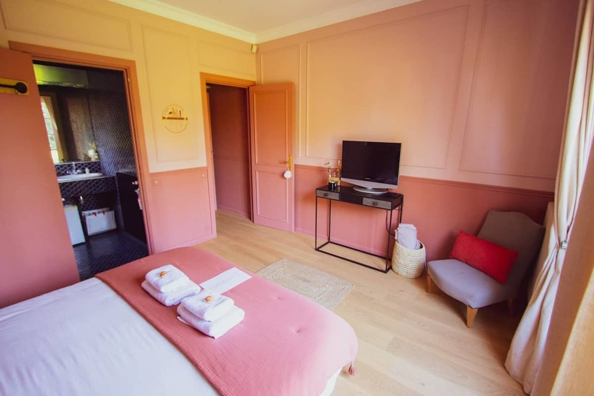 A hotel room with a bed, a TV, a small table, and a chair.