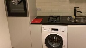 Cocina compacta con horno integrado, cocina a gas, lavabo y lavadora de carga frontal.