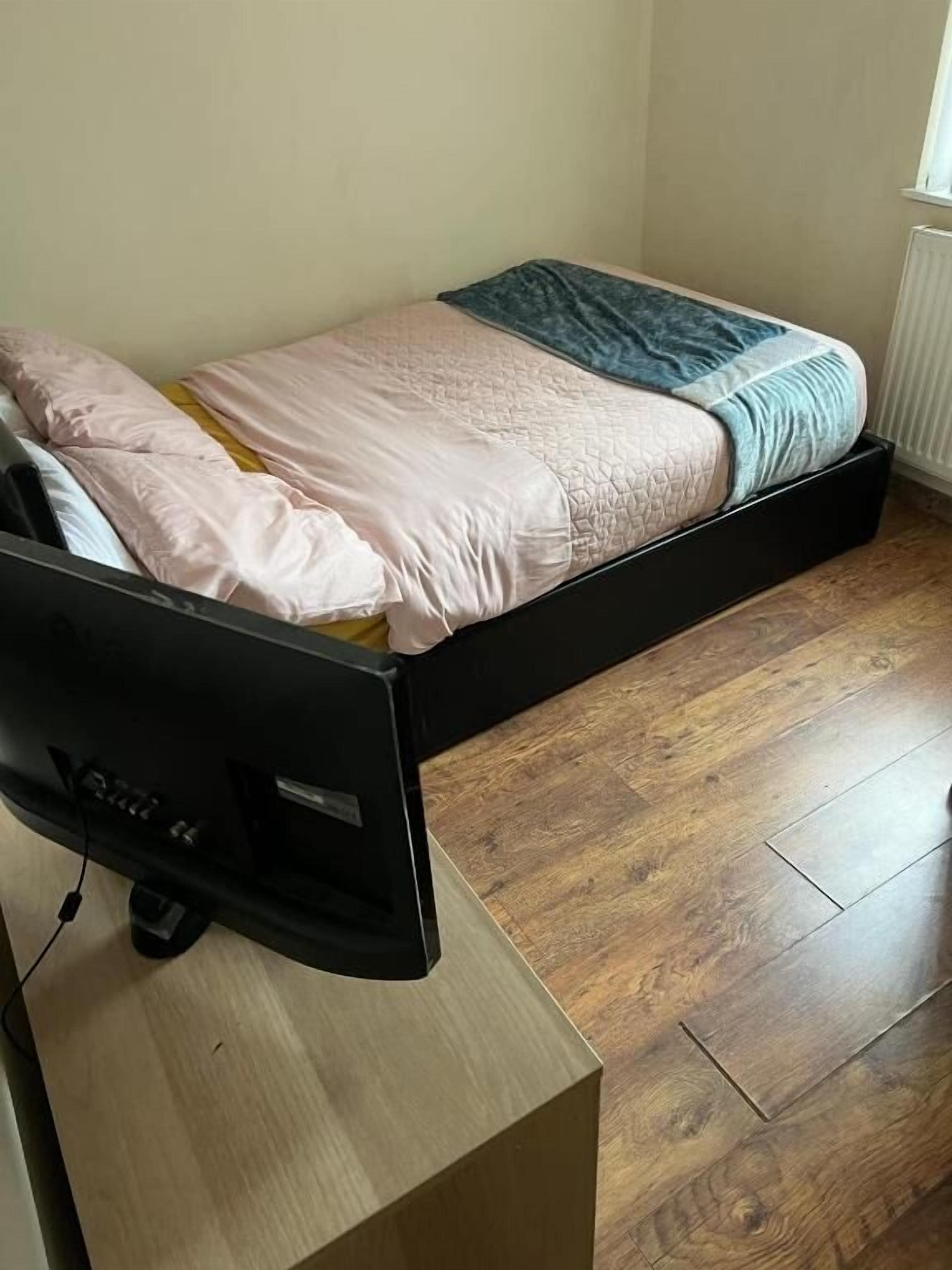 Een kleine kamer met een bed, bureau en radiator.