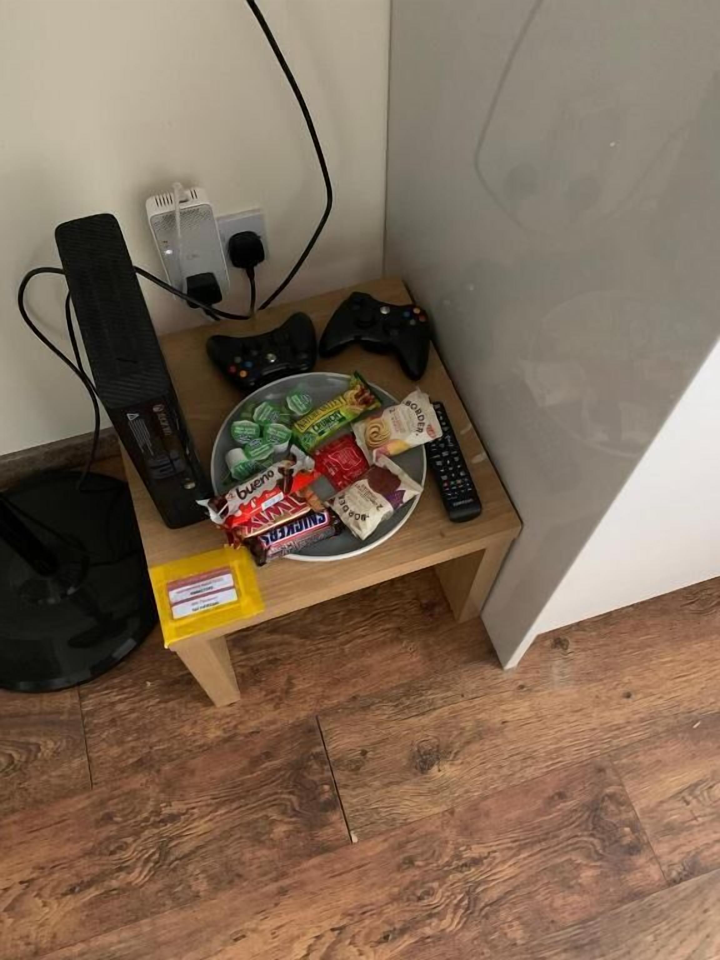 A small wooden table with snacks, a gaming controller, and a keyboard.