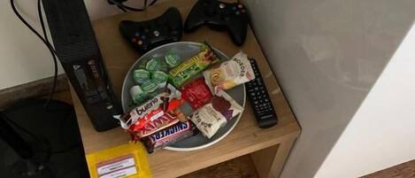A small wooden table with snacks, a gaming controller, and a keyboard.