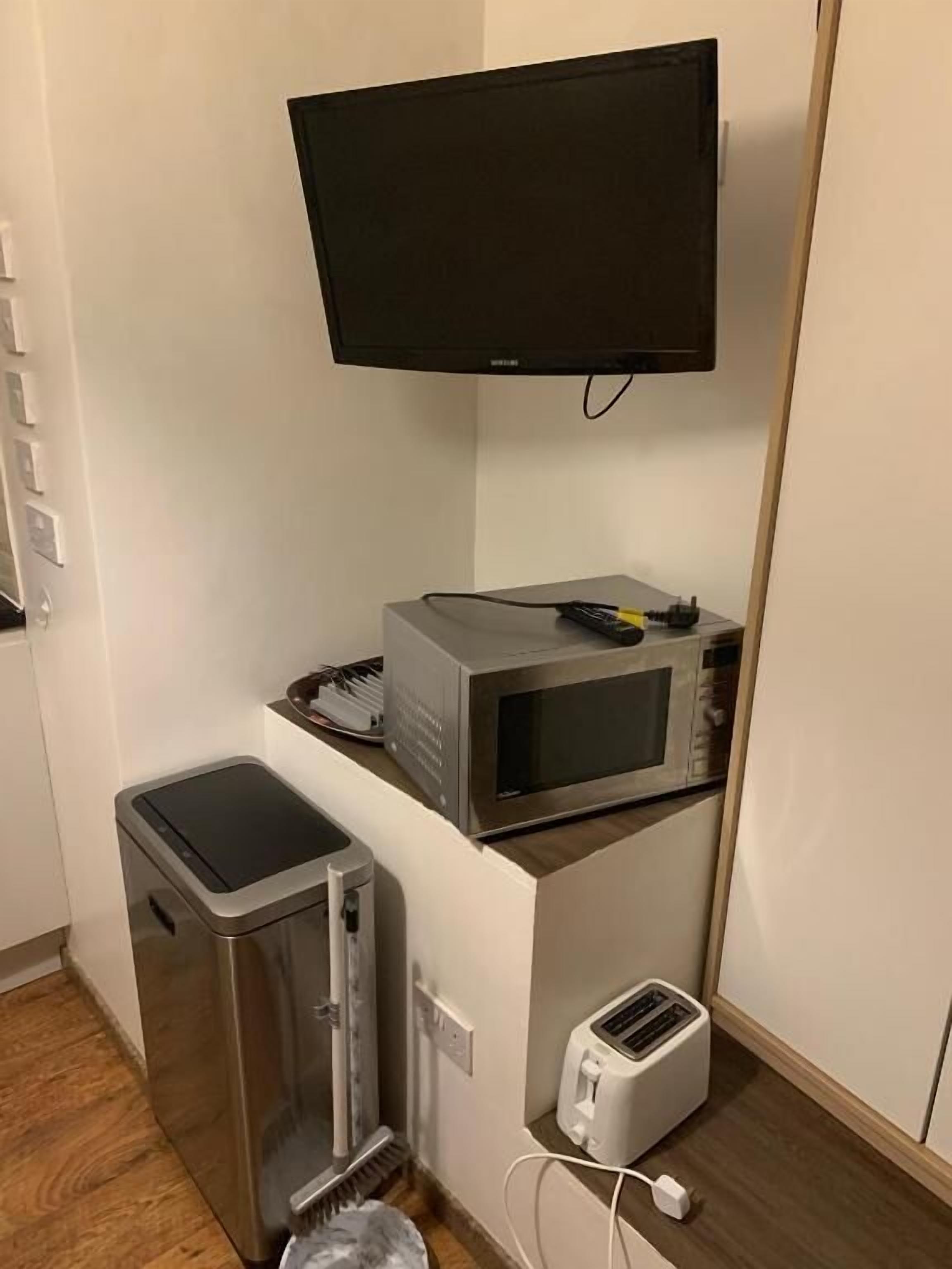 Une petite cuisine équipée d’un four à micro-ondes, d’un grille-pain et d’une petite poubelle.
