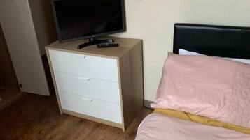 A bedroom with a bed, a nightstand, a television, and a wall-mounted mirror.