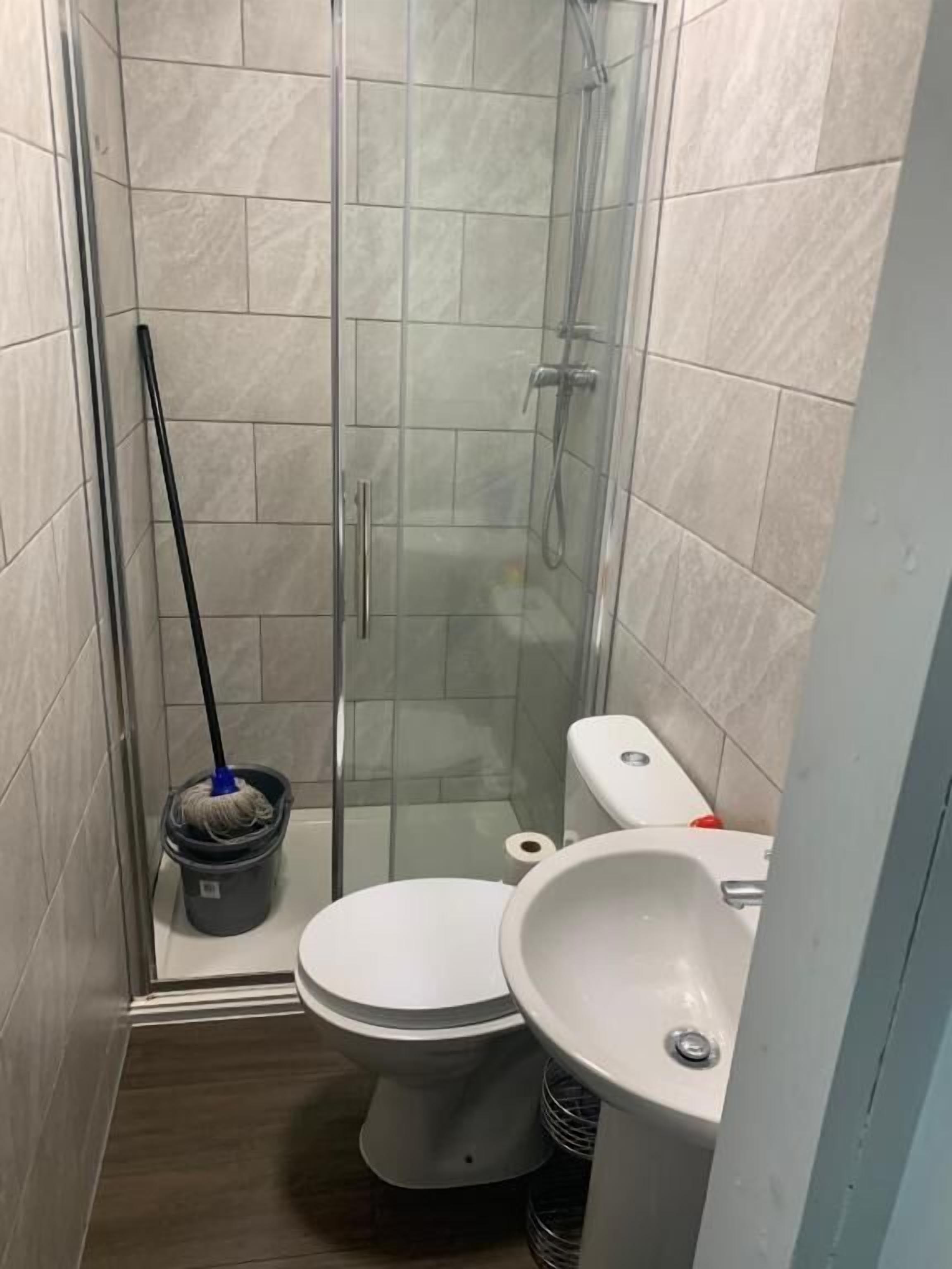 A small bathroom with a glass shower enclosure, a toilet, and a sink.