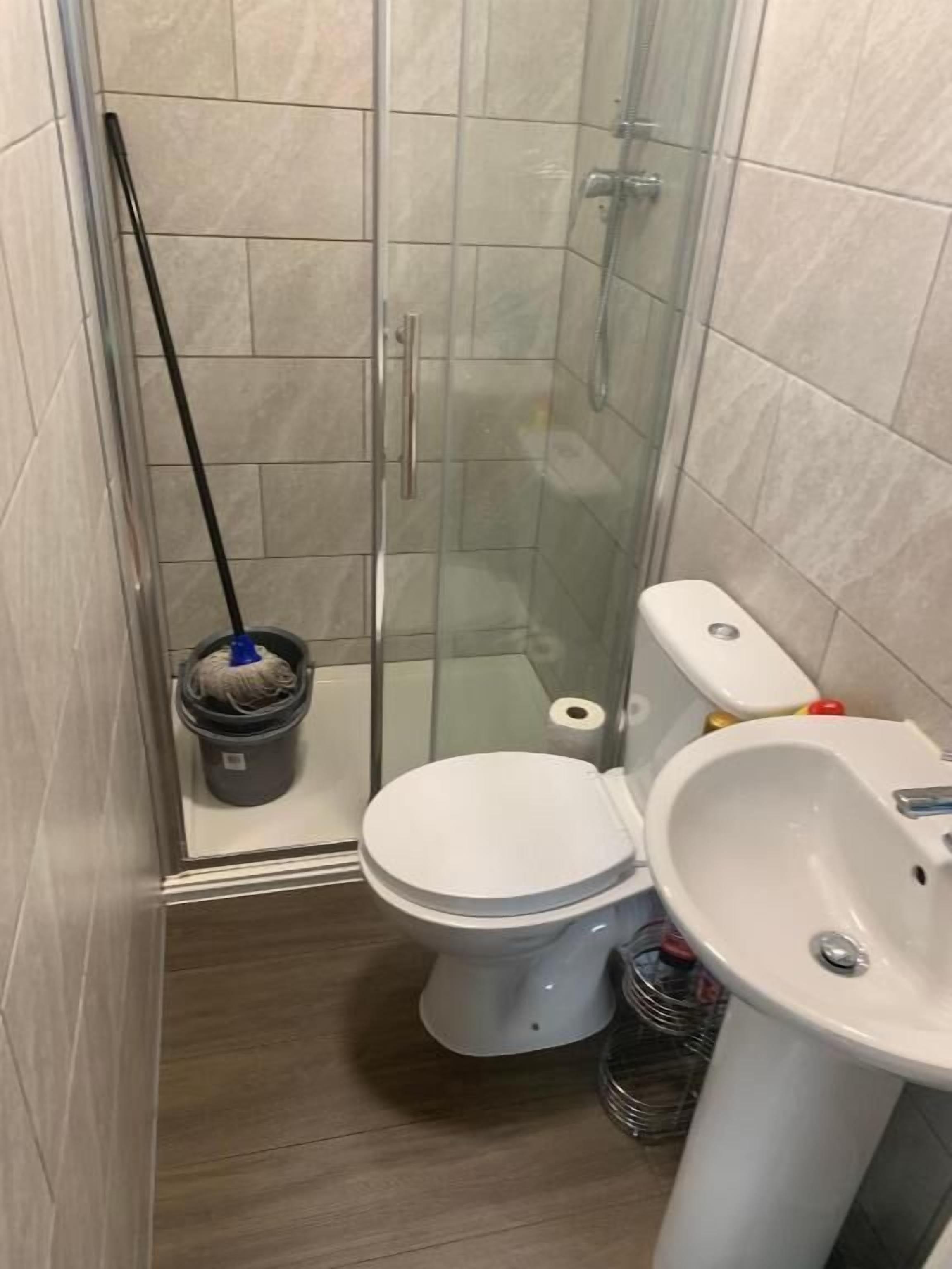 A small bathroom with a glass shower enclosure, a toilet, and a sink.