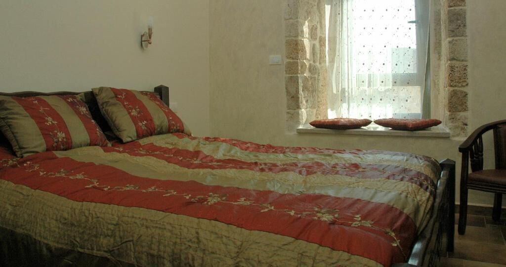 A bedroom with a bed, a chair, and a window with curtains.