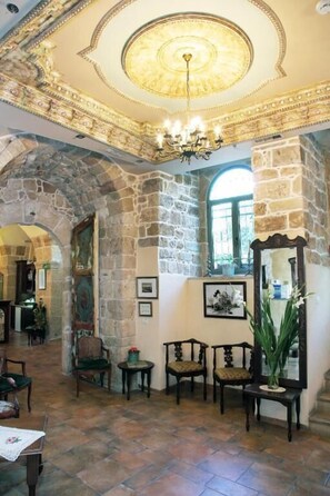 A room with stone walls, a chandelier, and a mirror. - AKKOTEL BOUTIQUE HOTEL (Acre)