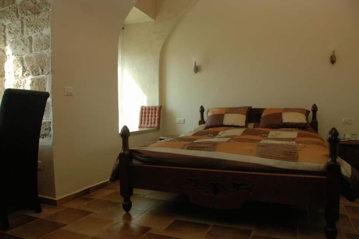Een slaapkamer met een houten bed, een stoel en een stenen muur.