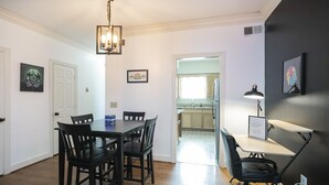A dining area with a wooden table and chairs, a pendant light, and a view into the kitchen. - 90's in Nash! 2bd Townhome in WEST END! 8 min ->DT! (Nashville)