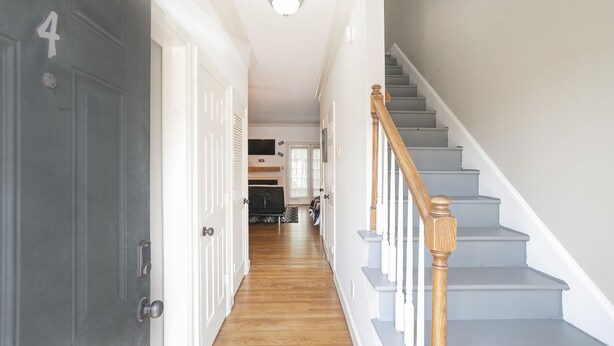 A hallway with a wooden staircase, white walls, and a door marked with the number 4. - 90's in Nash! 2bd Townhome in WEST END! 8 min ->DT! (Nashville)