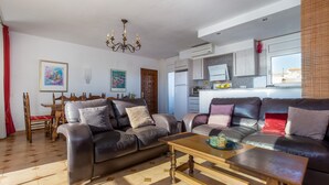 A living room with a sofa, coffee table, and a dining area with a table and chairs. - V020 - Puerto Primero (Empuriabrava)