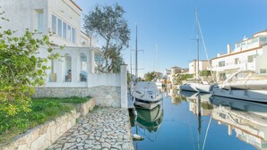 A marina with boats docked, stone pathway, and buildings with arched windows. - V020 - Puerto Primero (Empuriabrava)