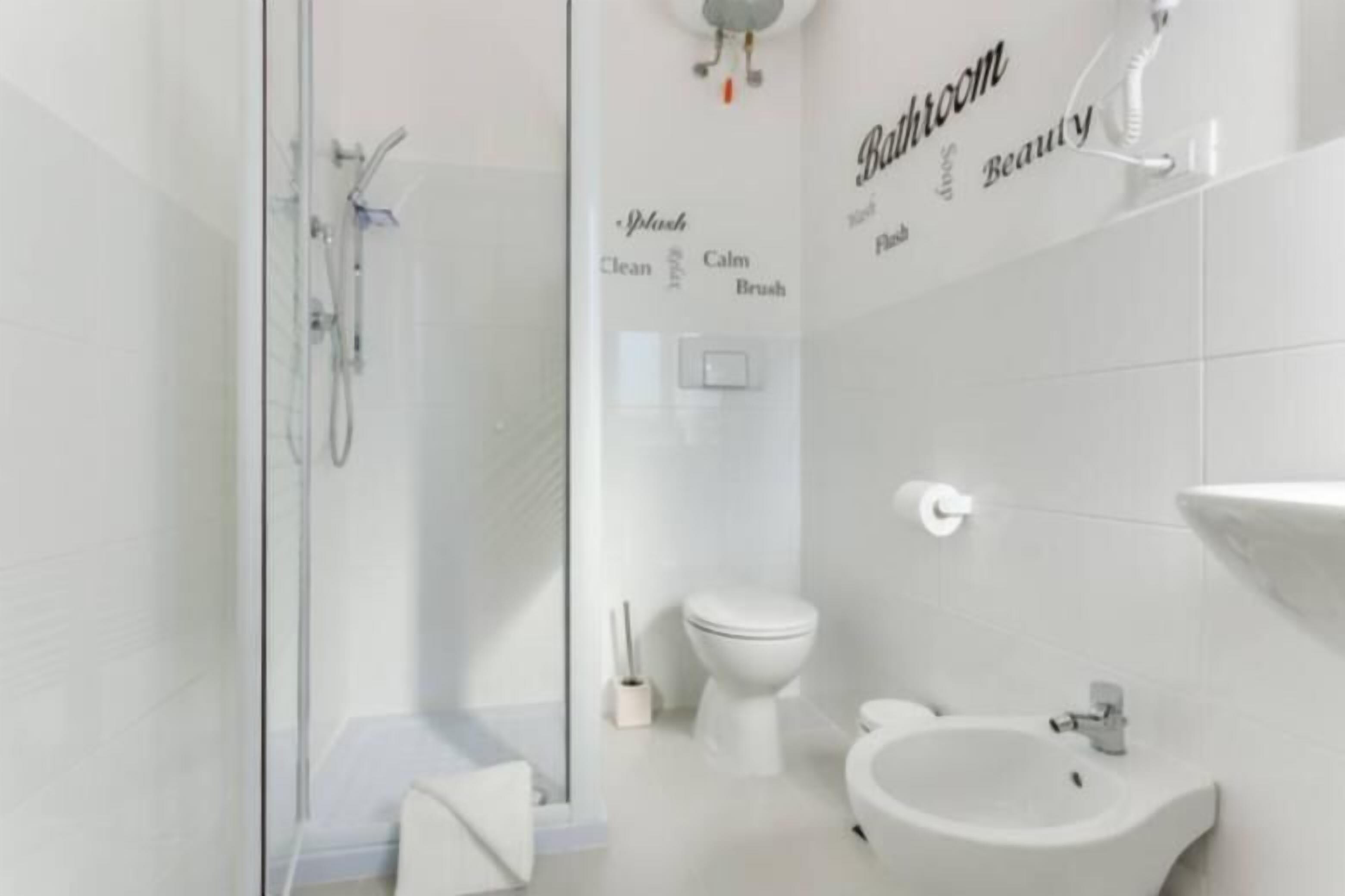 A modern bathroom with a glass shower enclosure, a toilet, bidet, and a sink.