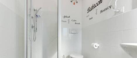 A modern bathroom with a glass shower enclosure, a toilet, bidet, and a sink.