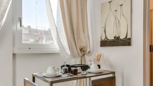 A room with a window, a table with a sign, and a painting on the wall.