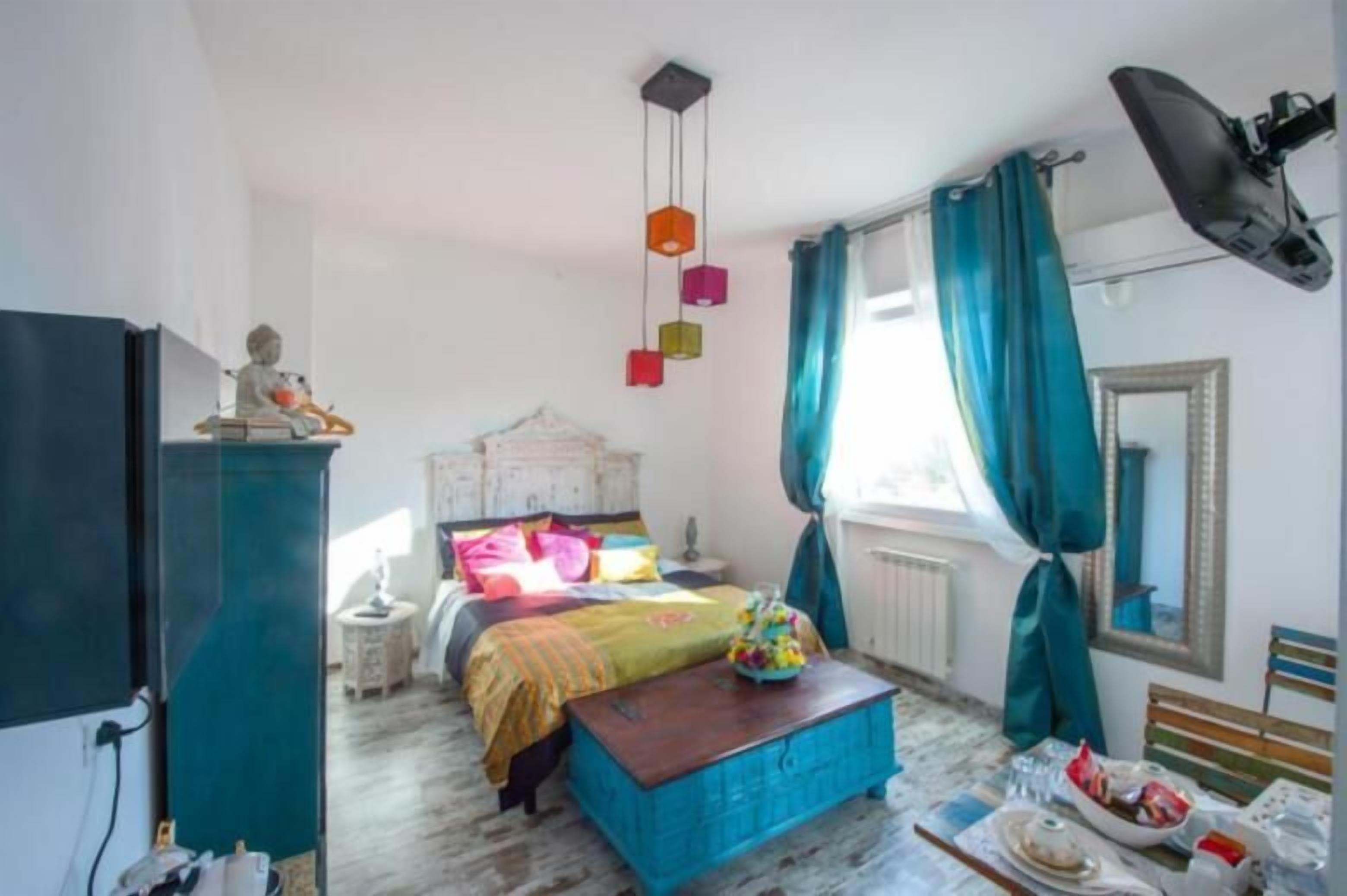 A bedroom with a bed, a dresser, a mirror, and a window with curtains.