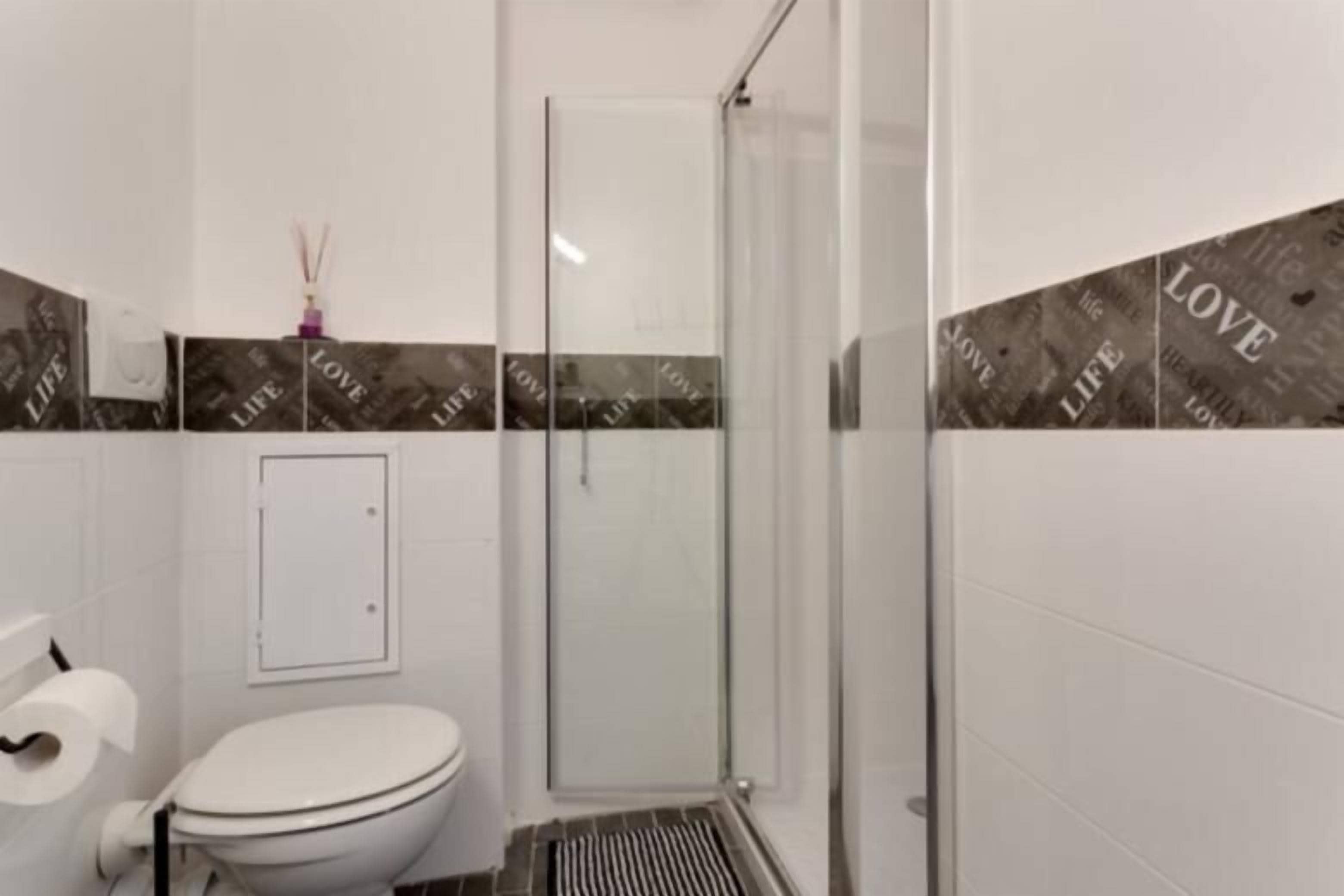 Ein modernes Badezimmer mit Toilette, Dusche und Glastür.