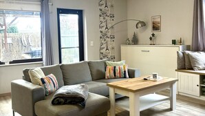 Un salon moderne avec un canapé gris, une table basse en bois et un meuble blanc.