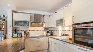 Une cuisine moderne avec des armoires blanches, des appareils en acier inoxydable et un plan de travail en bois.