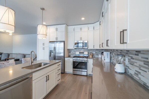 A modern kitchen with white cabinets, stainless steel appliances, and a tiled backsplash.