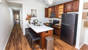 Una cocina moderna con armarios de madera, un refrigerador de acero inoxidable y una encimera de mármol.