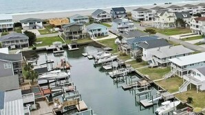 Un port de plaisance avec des bateaux amarrés, une jetée s’avançant dans l’eau et des immeubles résidentiels offrant une vue sur le littoral.