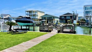 Une propriété située au bord de l’eau, dotée d’une terrasse en bois, de chaises longues et d’un petit espace abrité.
