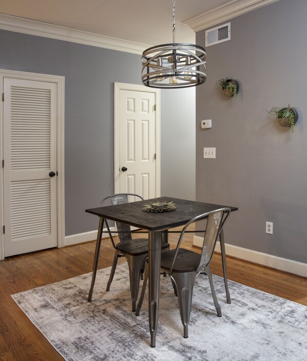 A dining area with a table, chairs, a chandelier, and a door.