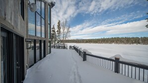 A snow-covered deck with a view of a forest and mountains. - Shoreline Lodge, Lakefront and hot tub (Island Park)