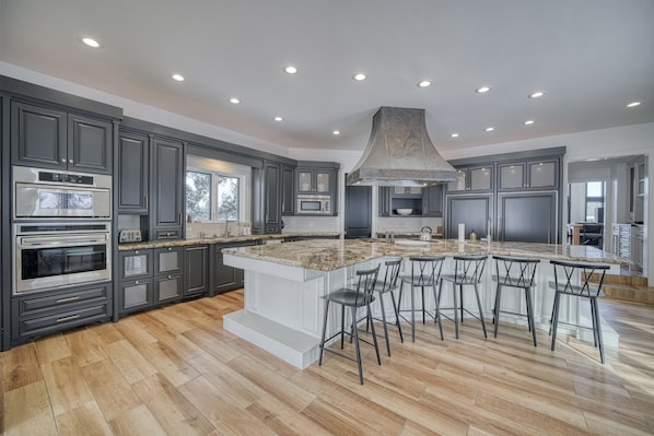A spacious kitchen with dark cabinetry, a large island with bar stools, and built-in appliances.