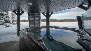 A hot tub under a wooden gazebo with a snowy landscape in the background. - Shoreline Lodge, Lakefront and hot tub (Island Park)