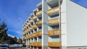A multi-story hotel with balconies, a parking area, and a mountainous backdrop. - 300m from ski slopes, 4th floor, balcony, parking, tv, ski locker, 38m², Les 2 Alpes (Les Deux Alpes)