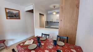 A dining area with a red tablecloth, wooden chairs, and a framed picture on the wall. - 300m from ski slopes, 4th floor, balcony, parking, tv, ski locker, 38m², Les 2 Alpes (Les Deux Alpes)