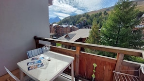 A balcony with a table, chairs, and a glass of water. - 300m from ski slopes, 4th floor, balcony, parking, tv, ski locker, 38m², Les 2 Alpes (Les Deux Alpes)