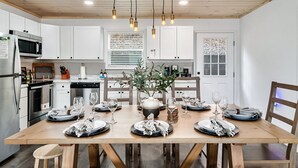 Una cocina moderna con armarios blancos, techo de madera e iluminación colgante.