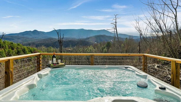Un jacuzzi con cubierta de madera y vista a las montañas.